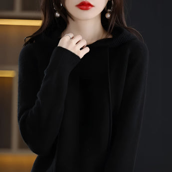 
A woman wearing a pink hooded sweater made of soft knit material, showcasing the cozy winter wear pullover in a Nero color, size 2XL. The sweater features long sleeves and a comfortable fit around the neck and shoulders.
