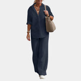 
A woman wearing a marine blue linen suit featuring a button-down shirt and matching trousers, suitable for a casual summer look.
