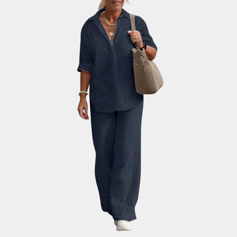 
A woman wearing a marine blue linen suit featuring a button-down shirt and matching trousers, suitable for a casual summer look.