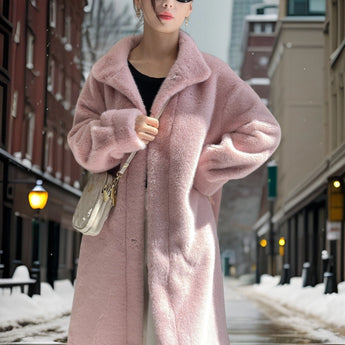 Women's oversized pink teddy coat shown in a winter setting, highlighting its plush texture and fashionable design. The coat features a collar, long sleeves, and falls at the waist, ideal for cold weather. The model wears the coat in a snowy environment, emphasizing its suitability for winter fashion.