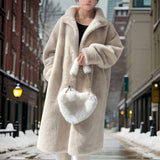 A cozy women's oversized teddy coat in beige, featuring plush fur-like material with long sleeves and a wide collar, designed for winter fashion.