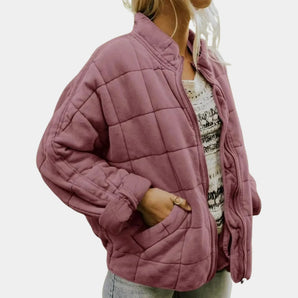 Women's pastel pink quilted bomber jacket with a front zipper, featuring a lightweight design and ribbed collar, cuffs, and hem.