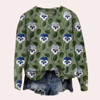 A women's crewneck sweater in a vibrant purple color featuring intricate floral embroidery, displayed on a plain background. The sweater has long sleeves and a classic crew neckline, offering a stylish and cozy look.