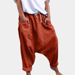 Women's red bohemian harem pants with an elastic ankle and drawstring waist, displayed on a hanger against a plain background.