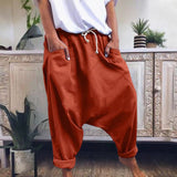 A pair of women's red bohemian harem pants with elastic ankles and a drawstring waist, displayed in an orange color in size XL, against a backdrop featuring houseplants and flowerpots.