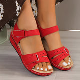 Women's red leather buckle sandals displayed on feet, highlighting their stylish design and comfortable fit. The sandals feature a vibrant red color with a secure buckle, perfect for summer wear.