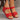 Women's red leather buckle sandals displayed on feet, highlighting their stylish design and comfortable fit. The sandals feature a vibrant red color with a secure buckle, perfect for summer wear.