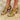 Women's red leather chunky heel strappy sandals with gold buckles on a foot, showcasing stylish design and bold color.