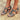 Women's red leather chunky heel strappy sandals with gold buckles worn on feet, highlighting the sandal design and gold buckle details against a natural background.