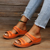 Women's orange leather platform sandals worn by a person, showcasing a fashionable and comfortable summer shoe design against a neutral background.