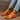 Women's orange leather platform sandals worn by a person, showcasing a fashionable and comfortable summer shoe design against a neutral background.