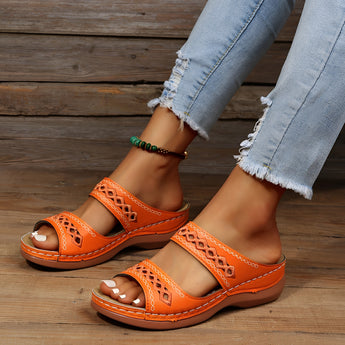 Women's orange leather platform sandals worn by a person, showcasing a fashionable and comfortable summer shoe design against a neutral background.