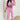 Women's pink tracksuit consisting of a cropped puffer jacket and drawstring joggers, worn by a model standing with arms slightly bent, showcasing the outerwear with sleeves and active pants, highlighting the fit around the waist and neck.