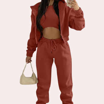 Women's red tracksuit featuring a cropped puffer jacket with long sleeves and drawstring joggers, showcasing a fashionable and sporty design.