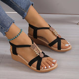 Women's black rhinestone wedge sandals on a model's feet, showcasing stylish summer fashion.