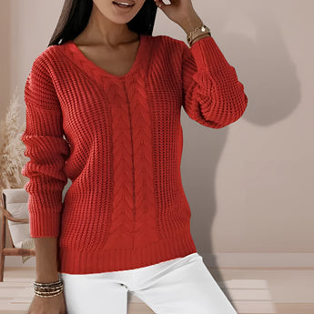 A woman wearing a sage green V-neck cable knit chunky sweater, showcasing the textured design on the sleeves and body, with a relaxed and cozy fit.