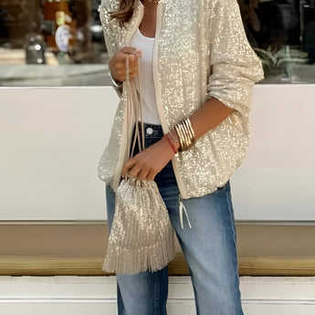 Women's white sequin blazer with long sleeves styled for an evening street look, showcasing glittery details over a denim outfit.