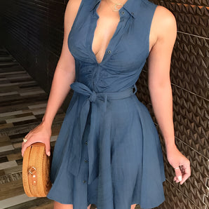 Women's sleeveless V-neck belted denim dress featuring pockets, highlighting its fitted waist and knee-length design.