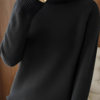 Women's black slim fit turtleneck sweater with ribbed cuffs, emphasizing a winter fashion style. The sweater features a high collar and long sleeves, offering a sleek and elegant look suitable for colder seasons.