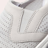 Women's lightweight and breathable slip-on walking sneakers in grey and beige, featuring arch support and a textile upper with a subtle pattern.
