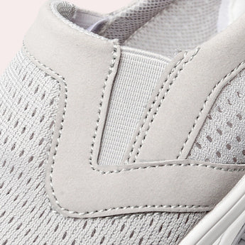 Women's lightweight and breathable slip-on walking sneakers in grey and beige, featuring arch support and a textile upper with a subtle pattern.