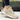 Women's grey sneakers with gold accents, shown in a casual chic style. The sneakers are designed for walking and outdoor activities, featuring a trendy and sporty look. The image conveys a sense of movement and athleticism.