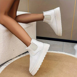 White platform high-top slip-on sneakers on a woman's feet, showcasing a stylish and comfortable design suitable for casual wear.
