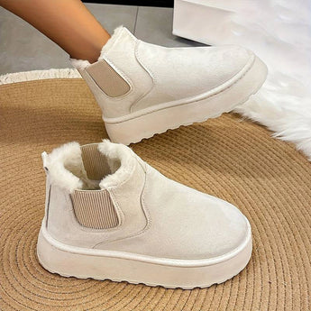 Women's stylish white platform high-top slip-on sneakers on a grey floor surface.