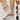 Women's beige suede ankle boots featuring a buckle strap and zipper with a low heel, styled with fashion-forward design elements.