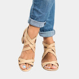 Women's tan leather strappy chunky heel sandals with a buckle strap, worn with jeans.