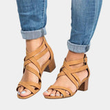 Tan leather strappy chunky heel sandals with a buckle strap, styled with denim jeans.