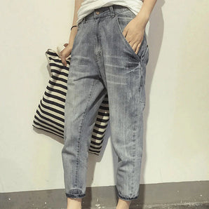 Women's light wash boyfriend jeans with a casual relaxed fit, highlighted by a focus on the thigh and knee areas, paired with a grey t-shirt.