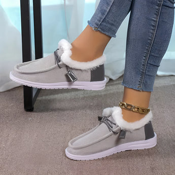 Women's turquoise slip-on shoes with fur lining, designed for winter wear, shown on a model wearing a grey dress.