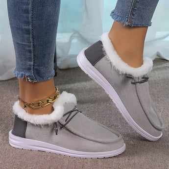 Women's turquoise fur-lined slip-on shoes with a stylish winter design, shown on a person wearing jeans.