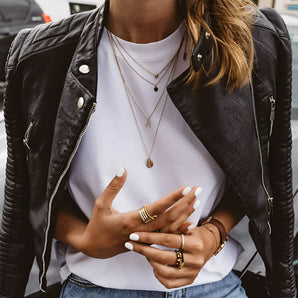 Women's urban chic black leather biker jacket with zippered front, featuring long sleeves and sleek design, worn by a model with sunglasses, embodying versatile streetwear fashion.