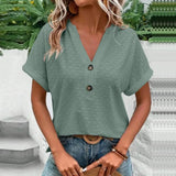 Woman wearing a short sleeve V-neck textured blouse with a geometric pattern, paired with jeans.