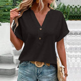 Woman wearing a short sleeve V-neck textured blouse with a geometric pattern, paired with jeans.