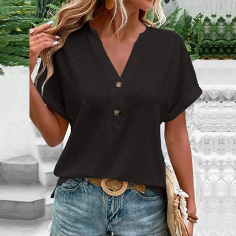 Woman wearing a short sleeve V-neck textured blouse with a geometric pattern, paired with jeans.