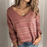 Light pink-gray women's V-neck sweater with white stripes, worn by a model with long hair, paired with jeans.