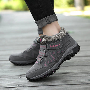 Women's black waterproof insulated hiking boots paired with grey jeans, showcasing a stylish and anti-slip design for outdoor activities.