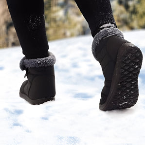 Women's grey waterproof insulated non-slip winter snow boots being worn, highlighting the footwear's design and coverage up to the knee, suitable for snowy conditions.