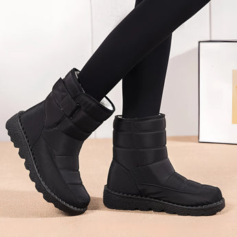 Women's waterproof insulated snow boots with non-slip soles, providing thermal protection and durability, shown on a model's legs.