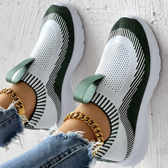 Women's white and black knit slip-on sneakers being worn with jeans, highlighting their breathable and lightweight design ideal for comfort and walking.