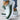 Women's white and black knit slip-on sneakers, featuring a lightweight and breathable design in a size 40.5, displayed in green color.