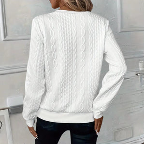 Women's white cable knit sweater worn as a stylish winter fashion pullover, featuring a cozy and textured design.