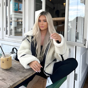 Women's white faux fur winter jacket with long sleeves, showcasing stylish street wear design; model wearing eyewear and shoes, highlighting comfort and fashion.
