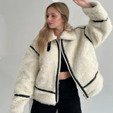 
A woman wearing a stylish and cozy white faux fur winter jacket. The jacket features long sleeves and a high collar, providing warmth and comfort. The woman is posing with her hands near her waist, showcasing the outerwear's chic design. The image highlights the jacket's fashionable appeal and winter-ready functionality, suitable for street wear.