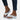 Women's white flat sandals featuring a rhinestone ankle chain, elegant summer fashion style displayed on a model's foot and leg.