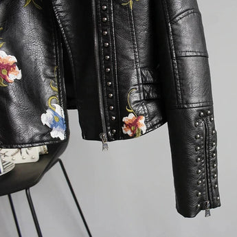 Women's white floral embroidered leather bomber jacket featuring a spring moto style with long sleeves, a collar, and intricate floral designs on the leather material.