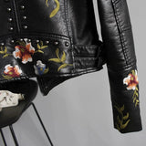 Women's white leather bomber jacket featuring floral embroidery, with sleeves and a collar, ideal for spring wear with a moto-inspired design.